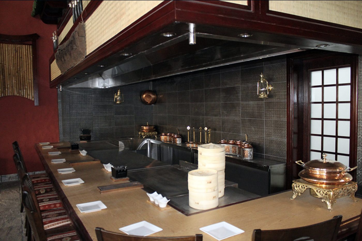 Teppanyaki cooking counter with stainless steel hood and surrounding seats