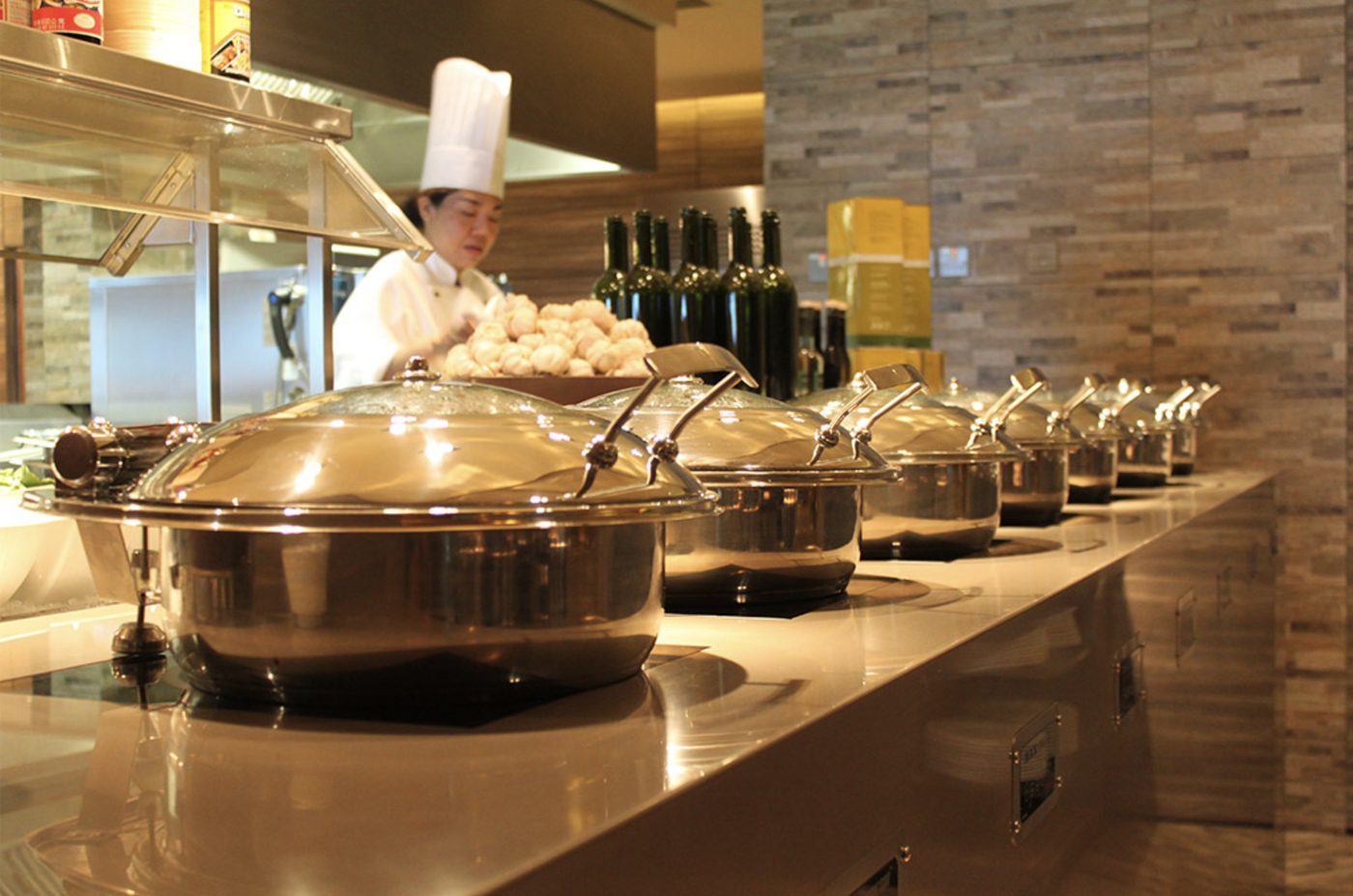 Buffet counter with chafing dishes and a chef preparing food