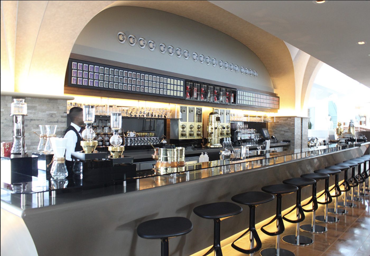Hotel café bar counter with coffee brewing equipment and black bar stools