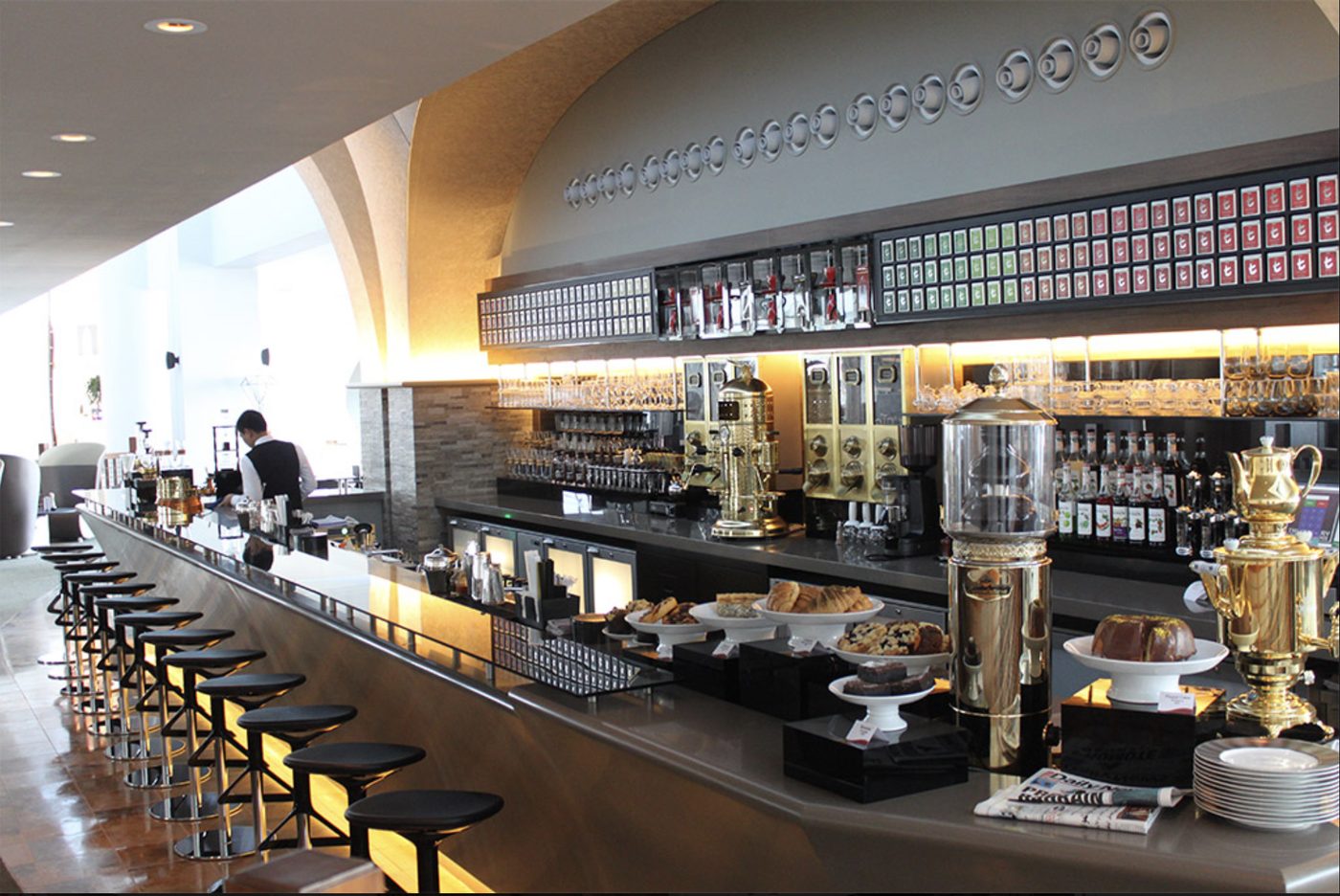 Hotel café counter with espresso machines, tea selection wall and pastries