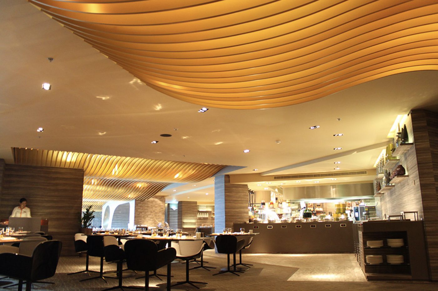 Hotel all-day dining restaurant with open kitchen and sculpted golden ceiling